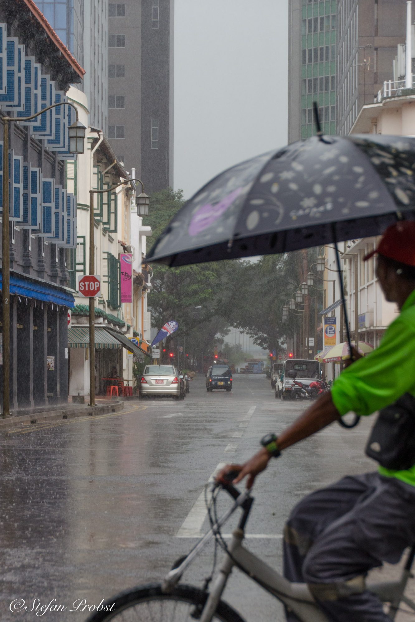Radfahren mit Regenschirm im Regen von Singapur