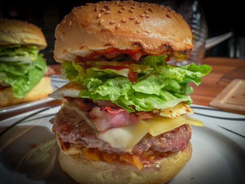 Burger mit Rinderpatty, Speck, Käse, Spiegelei und Salat